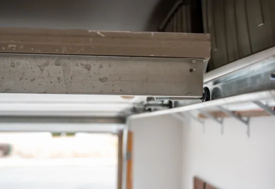Close-up view of a metal garage door track and rail system inside a residential garage, with the door partially open—ideal for those seeking expert Wisconsin garage door repair.