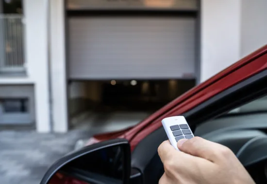 LiftMaster Launches Internet-Connected MyQ Commercial Door Operator AdobeStock 454971848 A person in a car uses a remote control to open a garage door, demonstrating the convenience that comes with professional Illinois garage door installation.