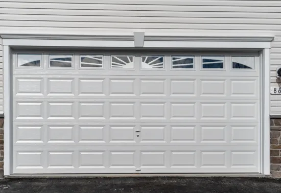 Should You DIY Garage Door Repairs? AdobeStock 329209147 White residential garage door with rectangular panels and small windows at the top, flanked by two wall-mounted lights and house number 8620 on the right—ideal for those seeking reliable Wisconsin garage door service.