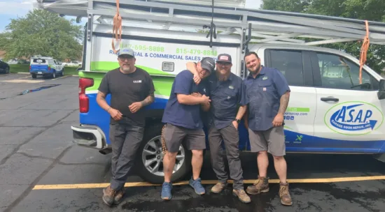 Remembering Harold “Butch” Poling tech day blog scaled e1783549288609 Four men in work uniforms pose smiling in front of an ASAP Roofing Repair truck parked in a lot, with ladders secured on top.
